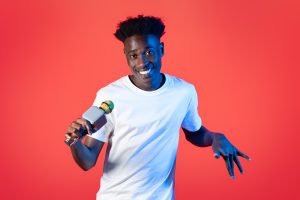 Funny young black guy comedian performing on red background