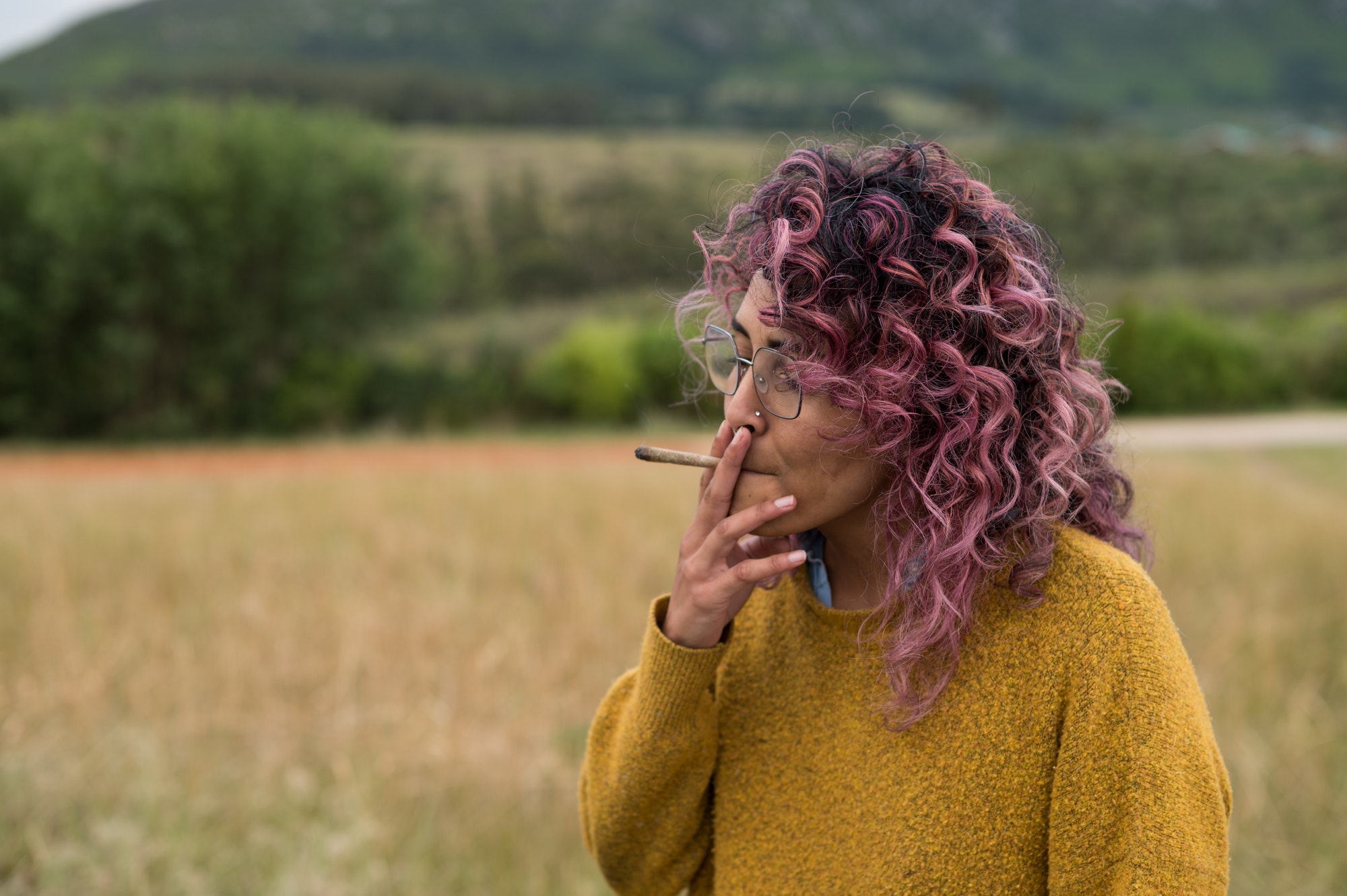 Portrait of woman standing and smoking a cannabis joint
